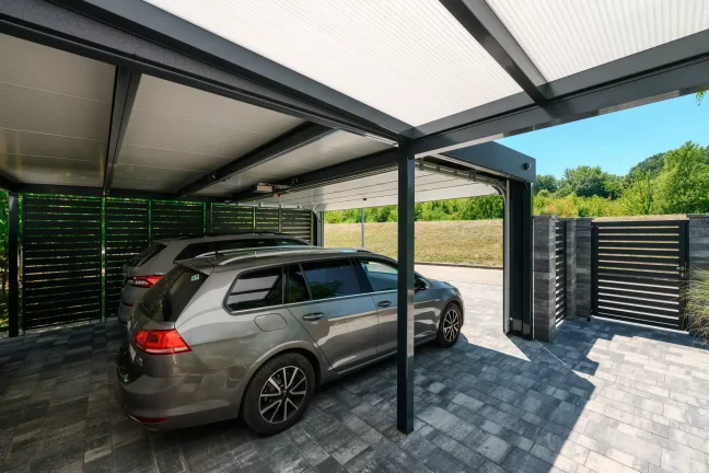 Blick vom Carport aus durch das geöffnete Tor auf eine Wiese