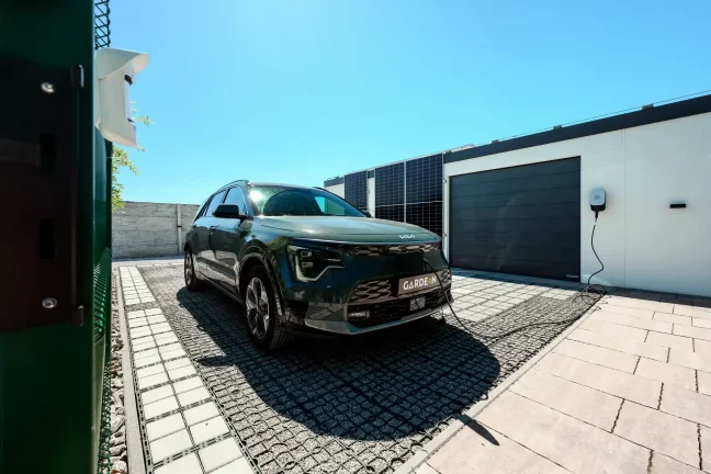 Grünes Auto an der Ladestation neben der Garage angeschlossen