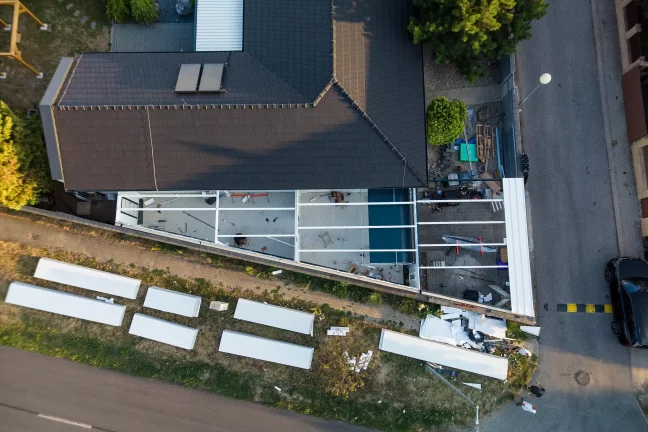 Luftaufnahme von oben mit Blick auf das Haus und die im Bau befindliche Stahlkonstruktion der Garage