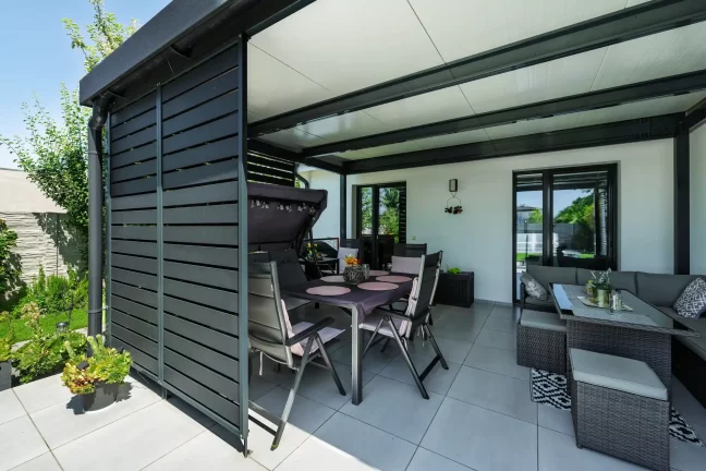 Detailansicht des gedeckten Tisches und Schaukelstuhls unter der Pergola
