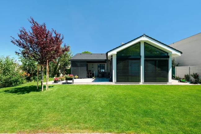 Rückansicht des Hauses mit schwarzer Lamellenwand der Pergola