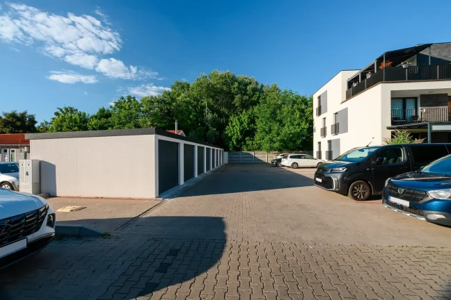 Garagenreihe mit Parkplatz, Autos und weißem Mehrfamilienhaus