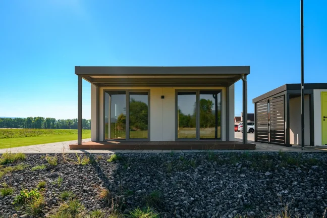 Tiny House von vorne mit überdachter Holzterrasse und Glasschiebetüren