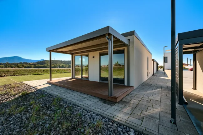 Überdachte Terrasse des Tiny Houses mit Bergblick und gepflastertem Weg entlang des Hauses