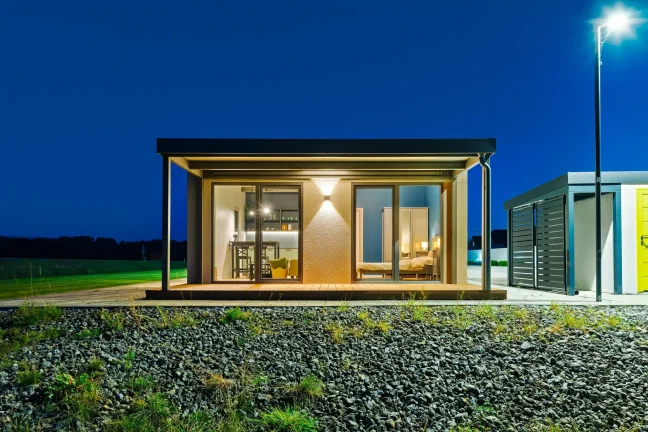 Tiny House von vorne am Abend mit beleuchteter überdachter Terrasse